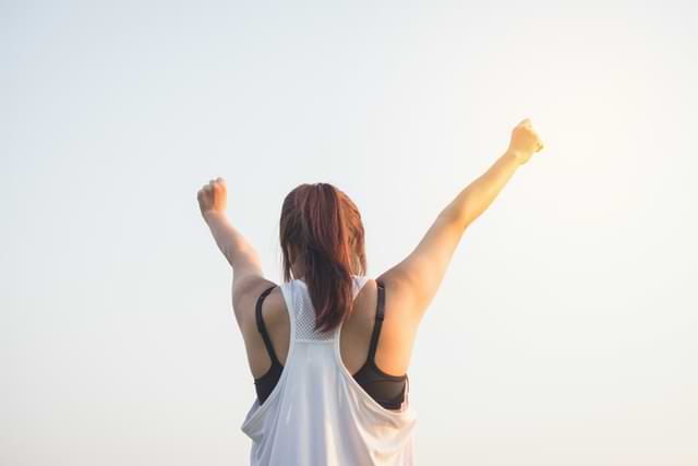 girl raising both hands up in the air