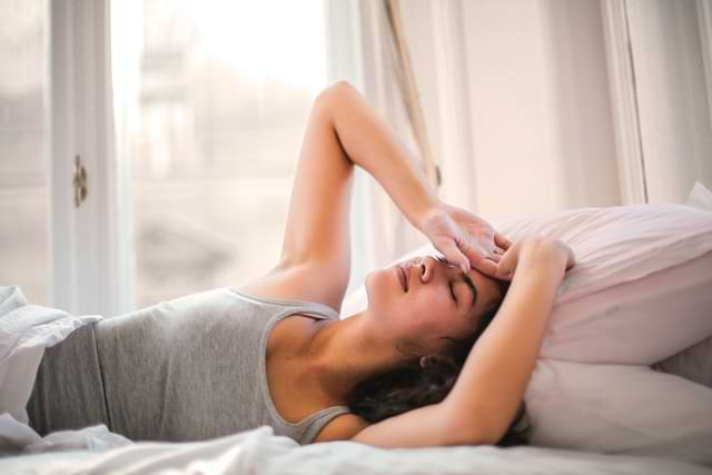 Girl Lying Down with Headache on Bed