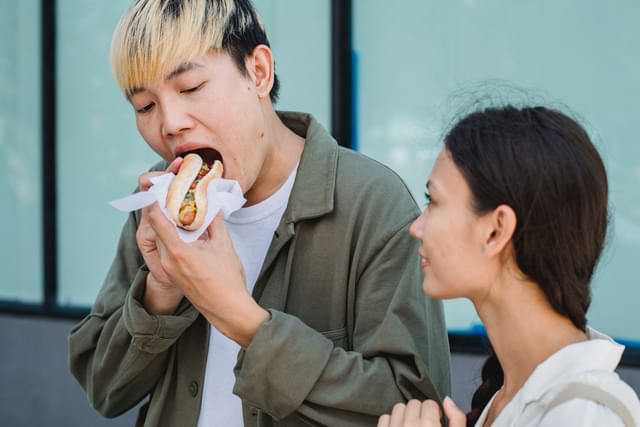 man eating food while friend watches