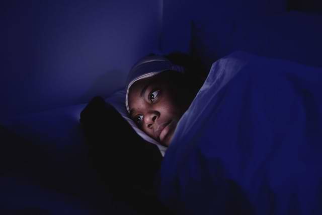 Gril Holding Phone In Bed In The Dark