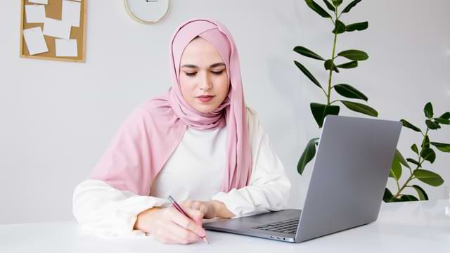 Lady in Hijab Writing at Her Desk