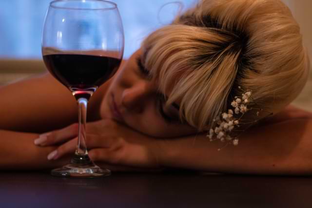 Woman Resting Head on Table with Wine Glass